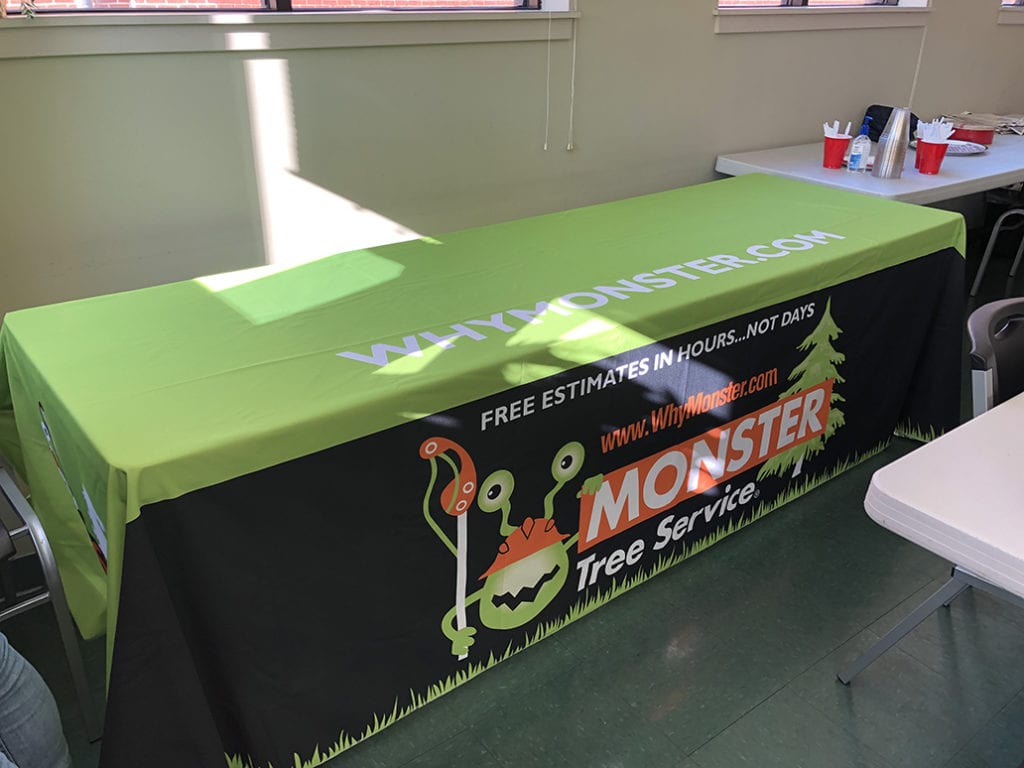 An image of a black and green table runner for Monster Tree Service.