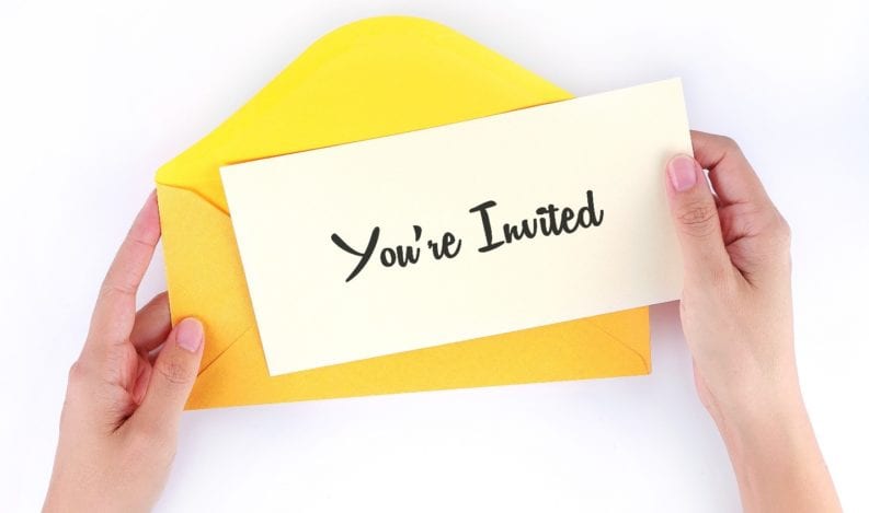 Hands holding an event invitation just received in an envelope