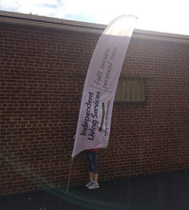 A woman places a temporary flag sign in front of a brick building