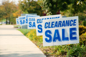 A white lawn sign with blue text that reads clearance sale.