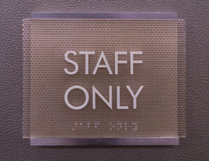 An image of a sign that reads staff only in raised letters and braille. 