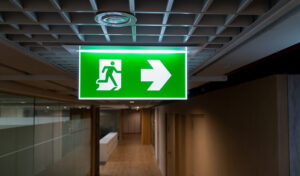 A bright green sign with a white stick figure running towards a door indicates an emergency exit.