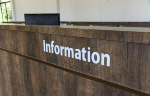 A photo of a reception desk with a sign that says Information in neat font across the front of the desk.