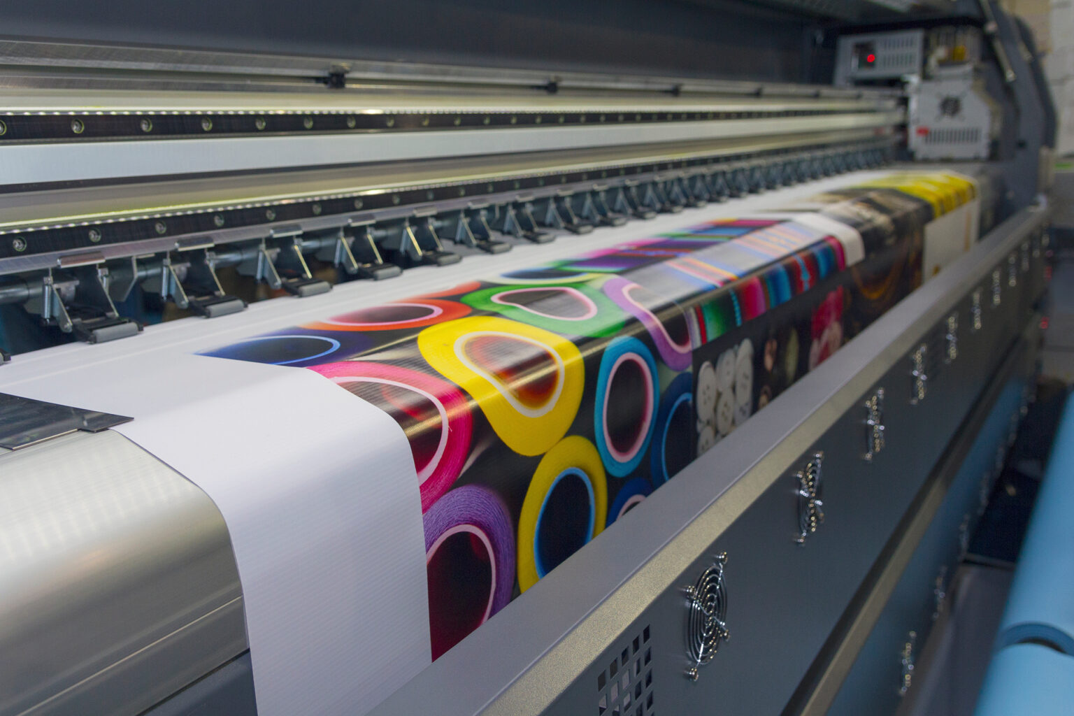 A large-scale printer prints a large multi-colored document.