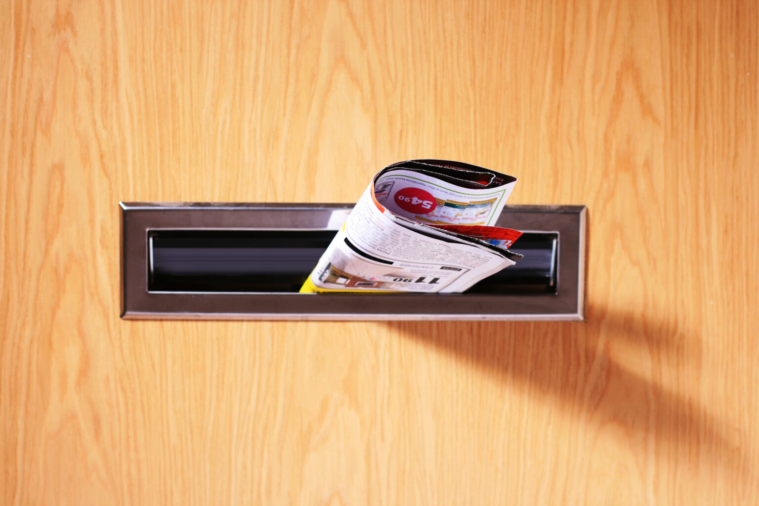 An image of a promotional flyer sticking out of a mailbox in a wooden door.