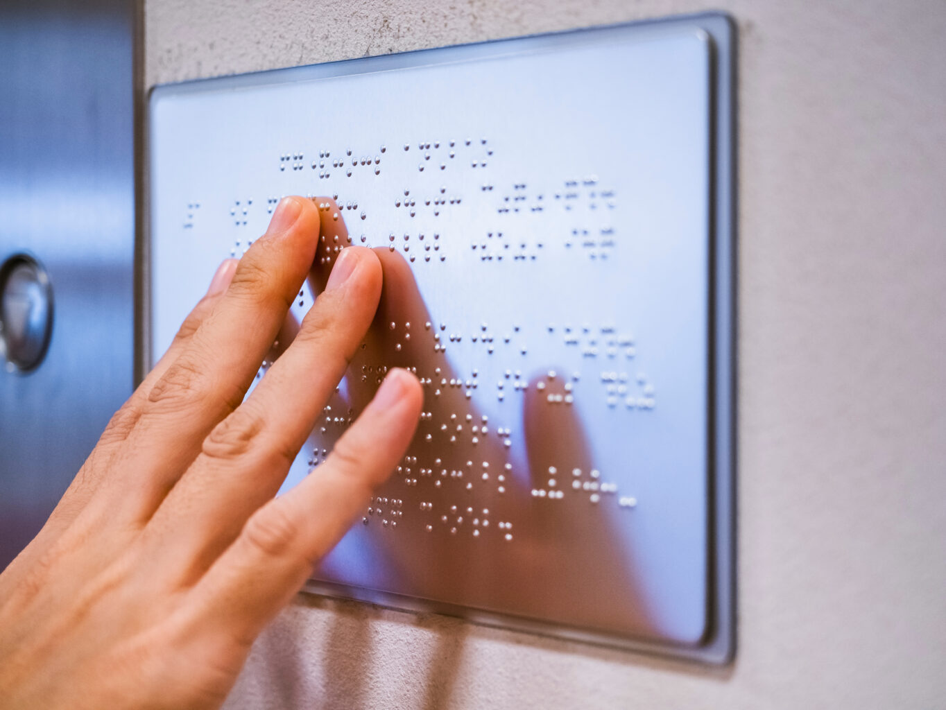An image of a person touching a sign that’s entirely braille