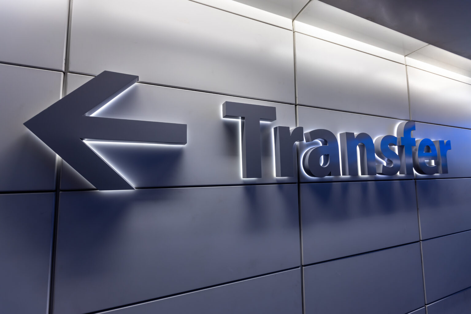 An image of a backlit “Transfer” sign with an arrow pointing