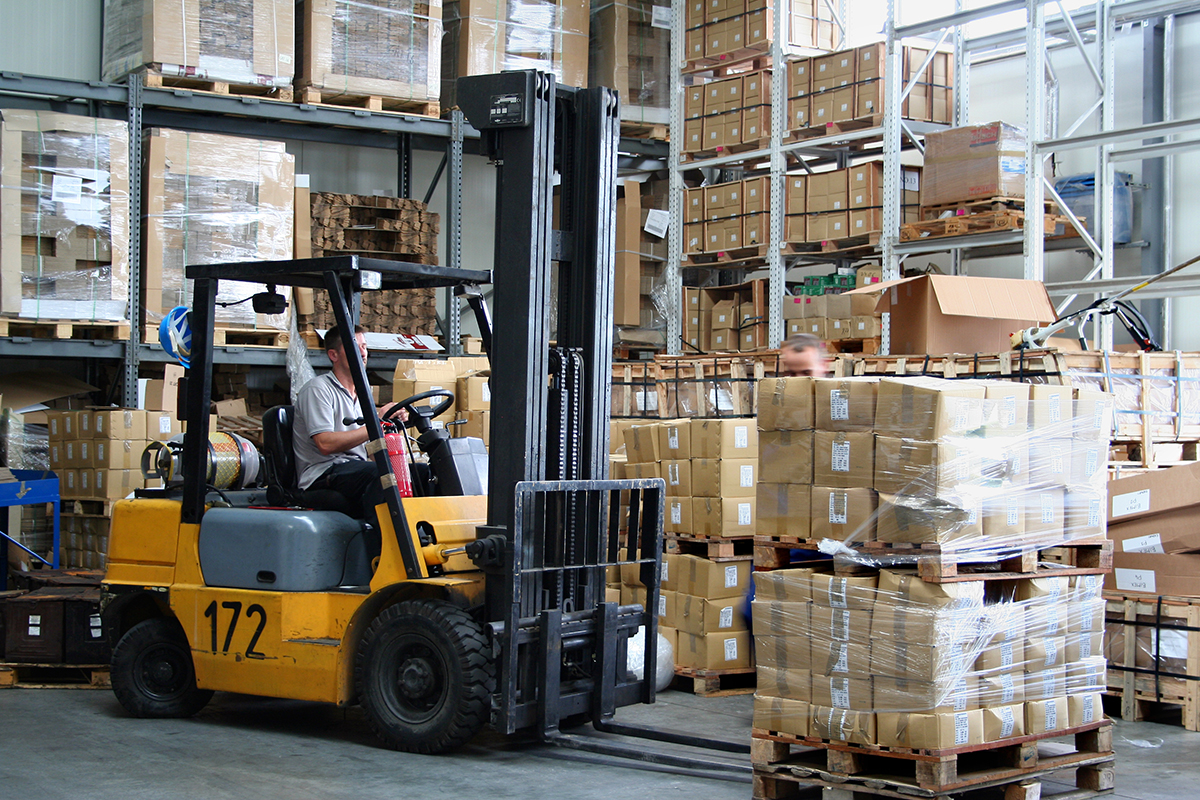 A person drives a yellow forklift around a warehouse.